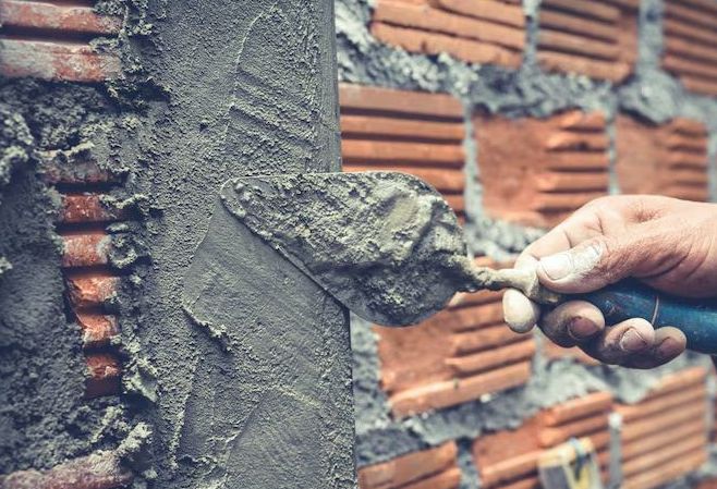 Fresh mortar being pressed into brick joints with a trowel